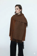 Woman wearing a brown poncho with fringe on a white background