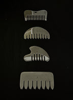 Four silver metal hair combs of varying sizes arranged vertically on a black background.