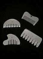 Four silver metal hair-combing attachments arranged on a black background, each with a different comb shape and a small engraved letter A.