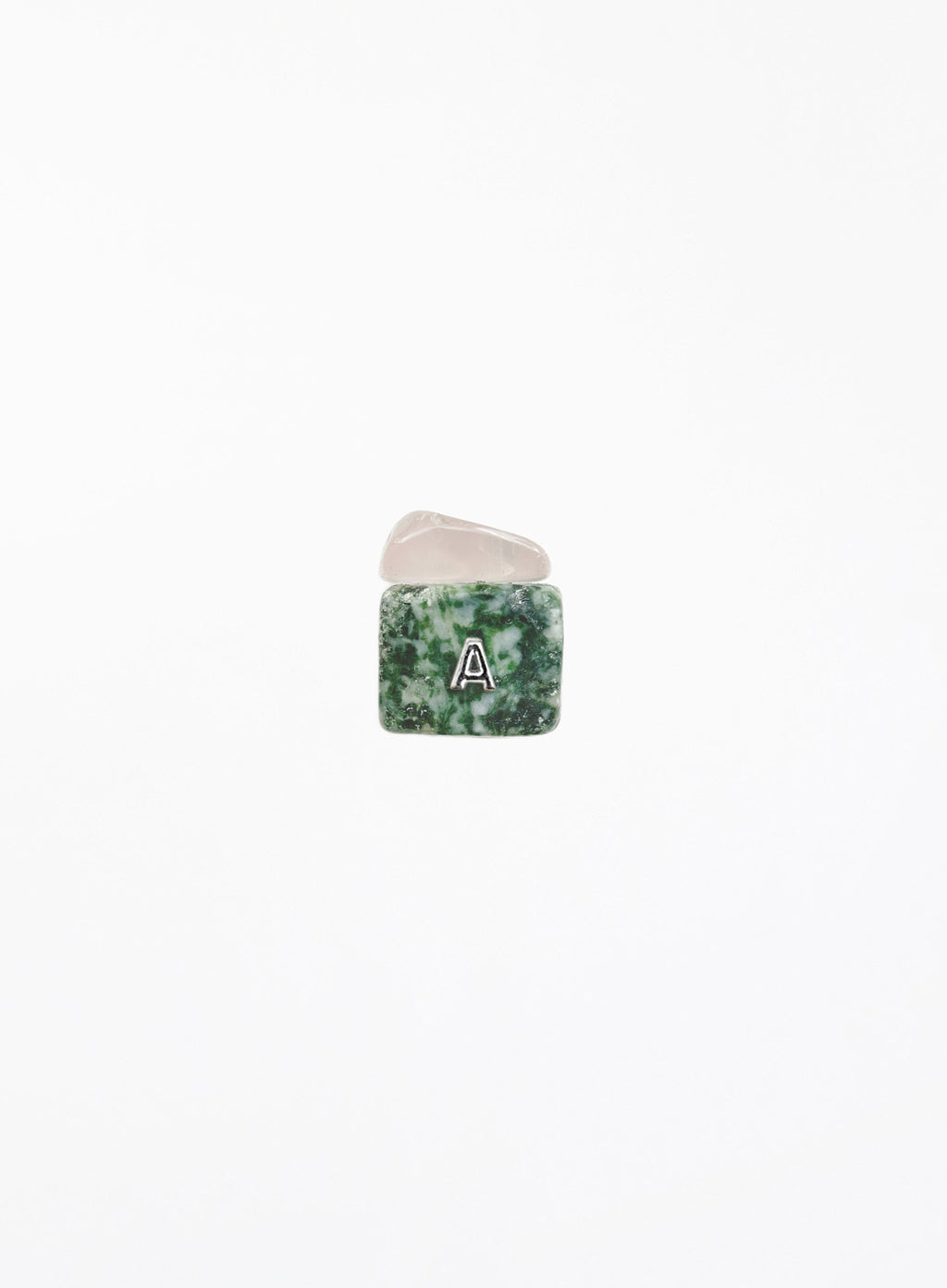 A small square gemstone charm with a green and white marbled pattern, featuring a white letter 'A' in the center, resting on a smooth, pale pink stone against a solid white background.