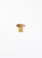 A small mushroom-shaped crystal set with a brown top and a yellow base featuring the letter 'A', centered on a plain white background.