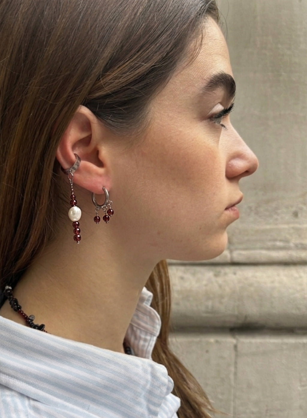 Close-up of a person wearing garnet earrings with a neutral background