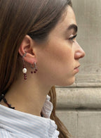 Close-up of a person wearing garnet earrings with a neutral background