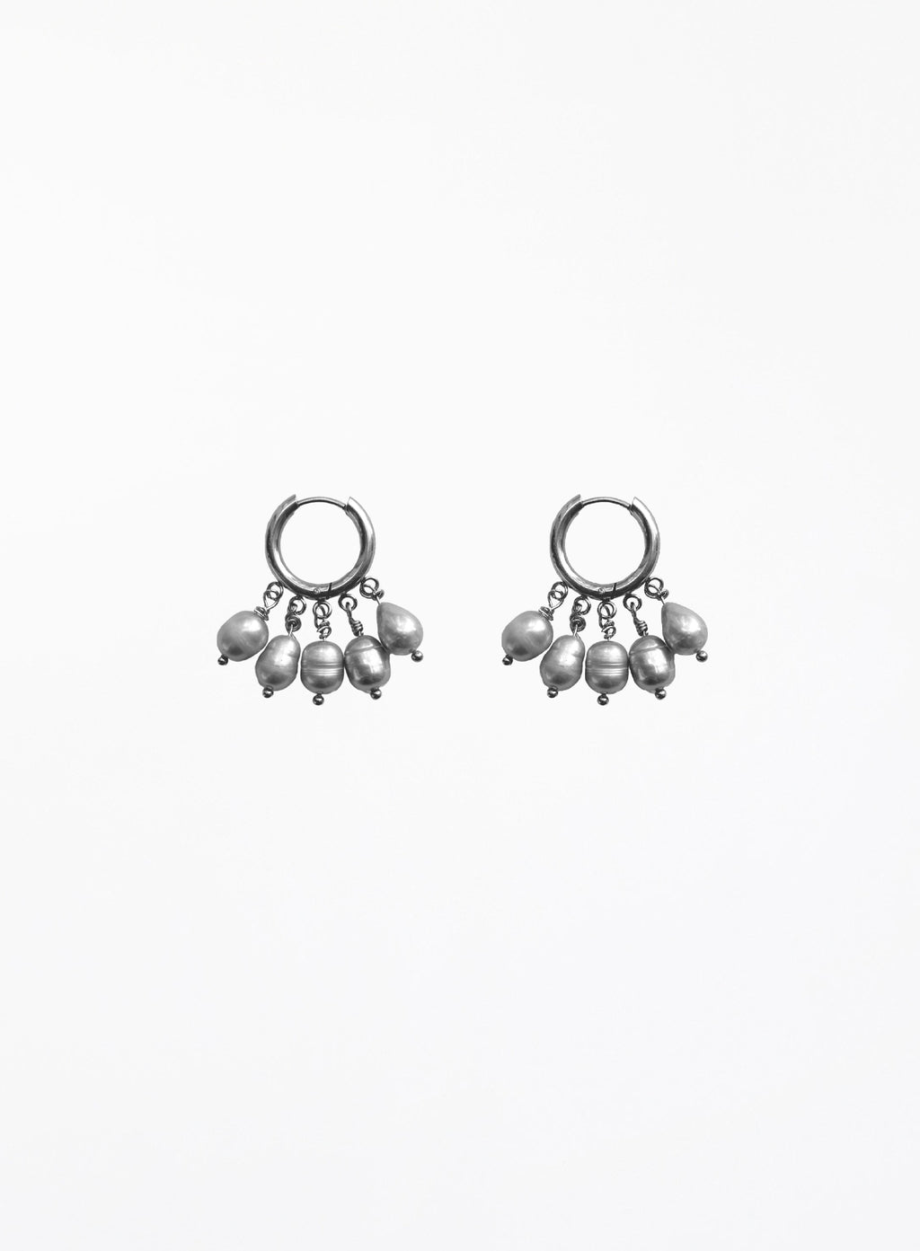 a pearl of grey pearl charms earrings in huggie hoop against white background