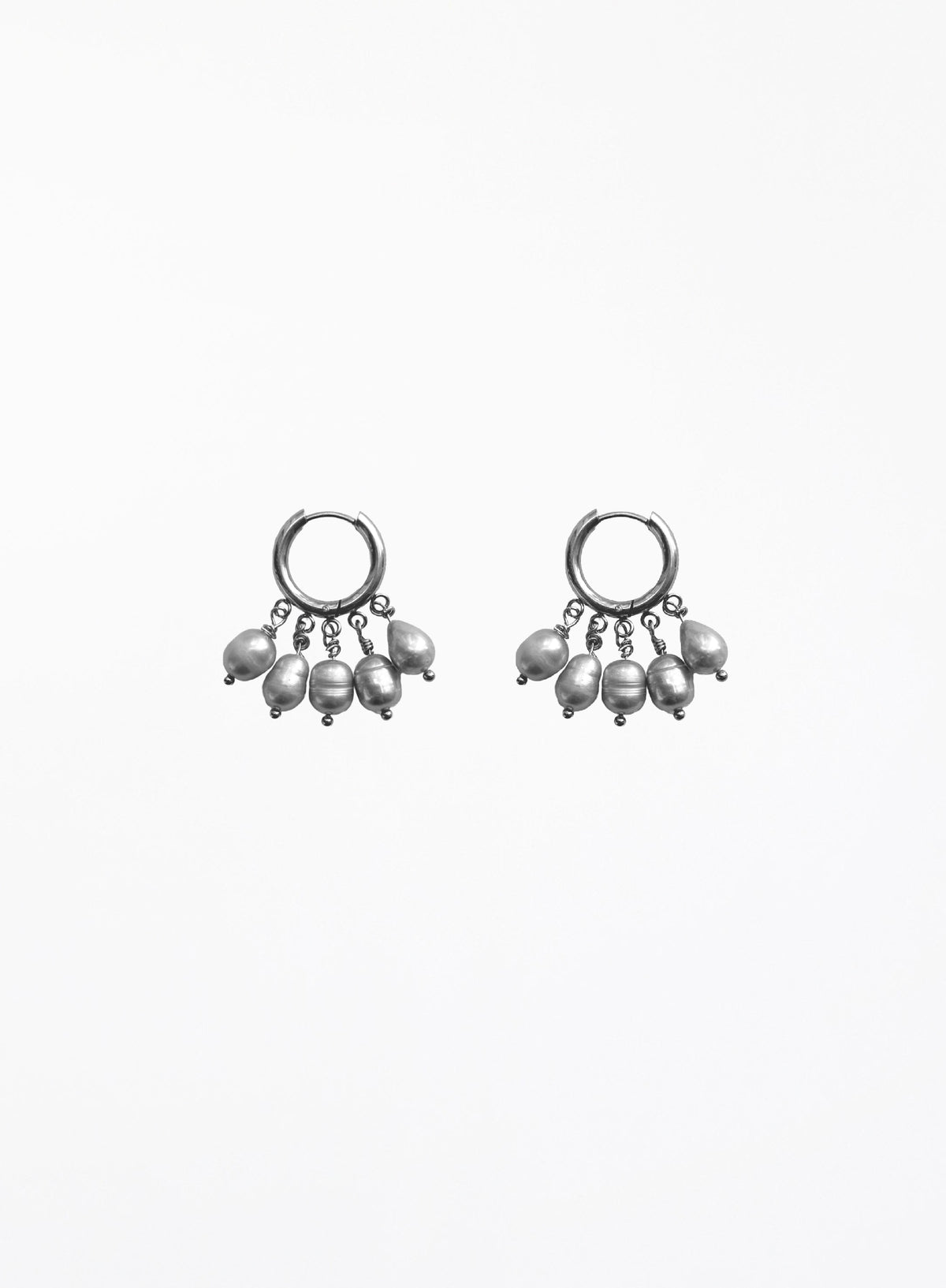 a pearl of grey pearl charms earrings in huggie hoop against white background