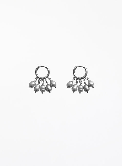 a pearl of grey pearl charms earrings in huggie hoop against white background