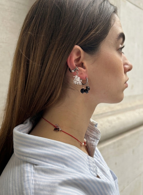 woman waering pearl earrings, ear cuff, and red cord necklace