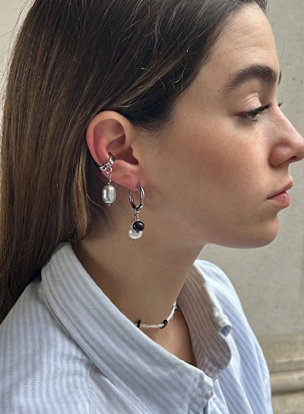close up shot of a woman with pearl earrings and grey pearl ear cuff
