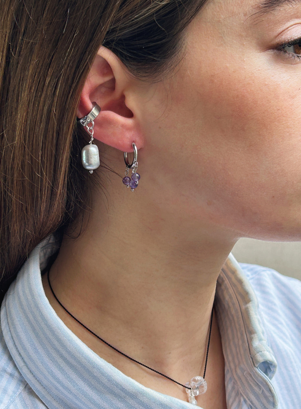 Close-up of a person wearing two earrings with a blurred background