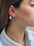 Close-up of a person wearing two earrings with a blurred background
