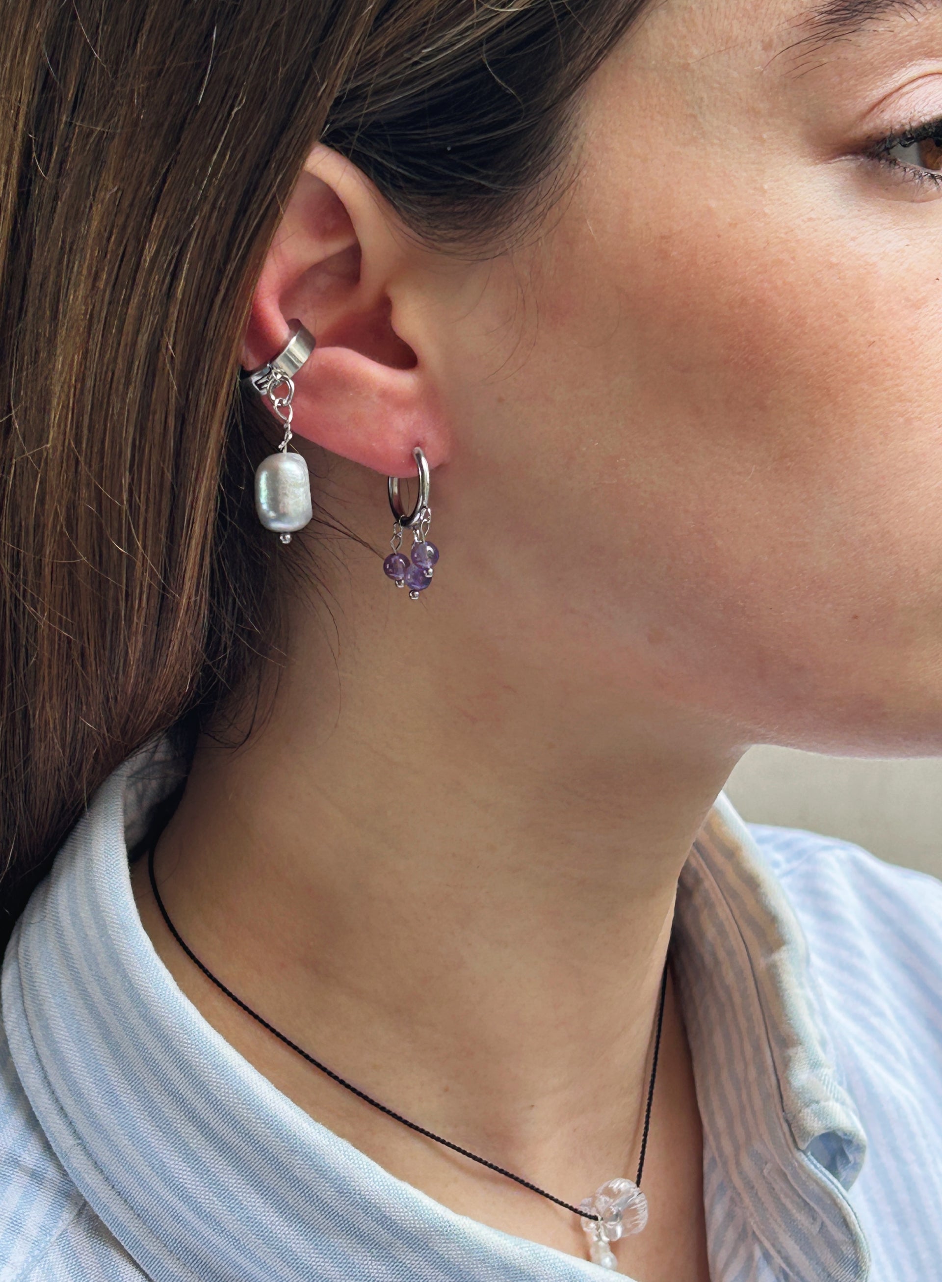 Close-up of a person wearing two earrings with a blurred background