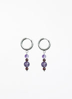 Pair of hoop earrings with purple beads on a white background