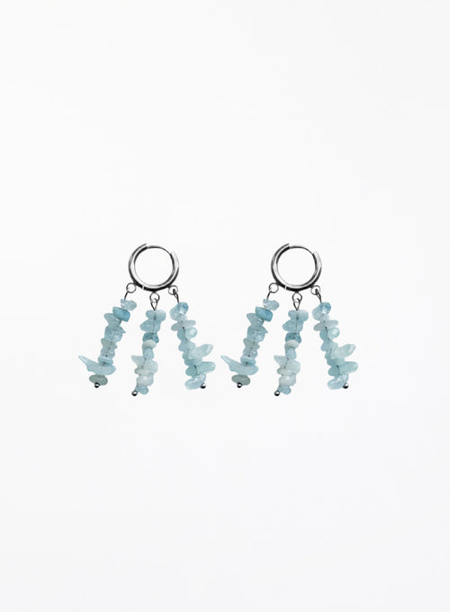 A pair of silver hoop dangle earrings with three strands of light blue chip stones hanging from each hoop, shown against a plain white background.