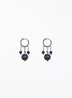 A pair of silver hoop earrings with dangling blue beads and dark round stones, shown against a plain white background.
