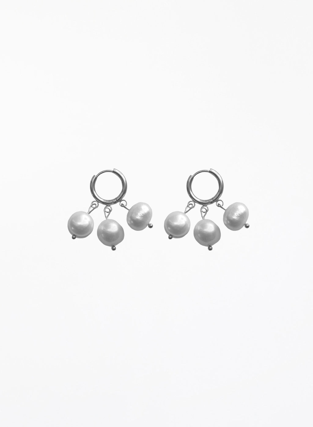 A pair of silver huggie hoop earrings with dangling baroque pearls, shown against a plain white background.