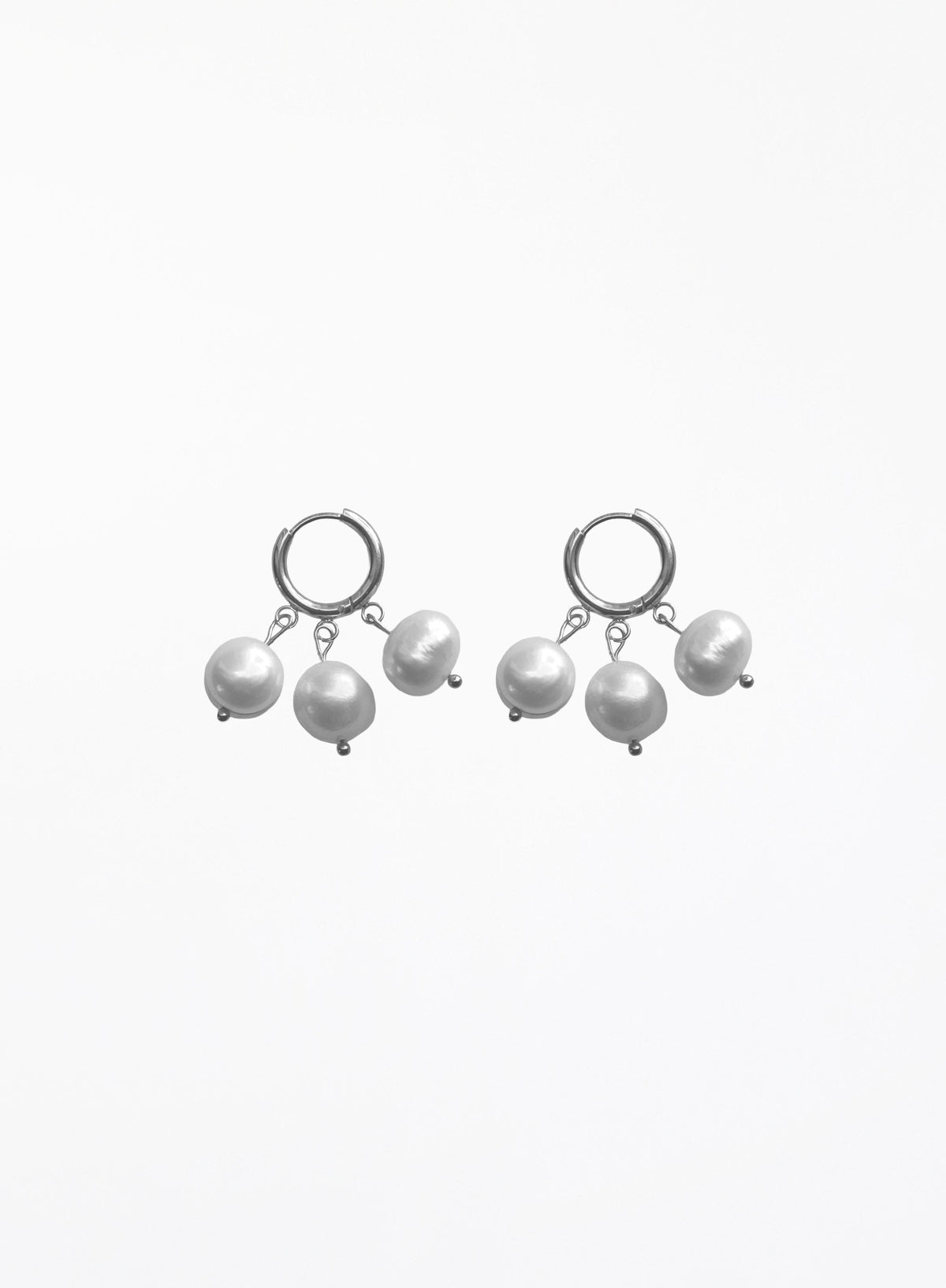 A pair of silver huggie hoop earrings with dangling baroque pearls, shown against a plain white background.