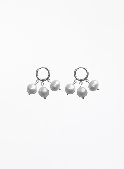 A pair of silver huggie hoop earrings with dangling baroque pearls, shown against a plain white background.