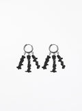 A pair of black dangle earrings with textured, irregularly shaped beads hanging from silver-toned hoop backings, shown against a plain white background.