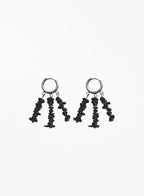 A pair of black dangle earrings with textured, irregularly shaped beads hanging from silver-toned hoop backings, shown against a plain white background.