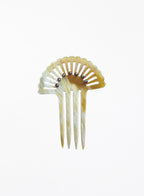 A decorative hair comb with a fan-shaped top, featuring a marbled amber and cream resin body, four tines, and a row of small dark metallic beads along the inner curve, set against a plain white background.