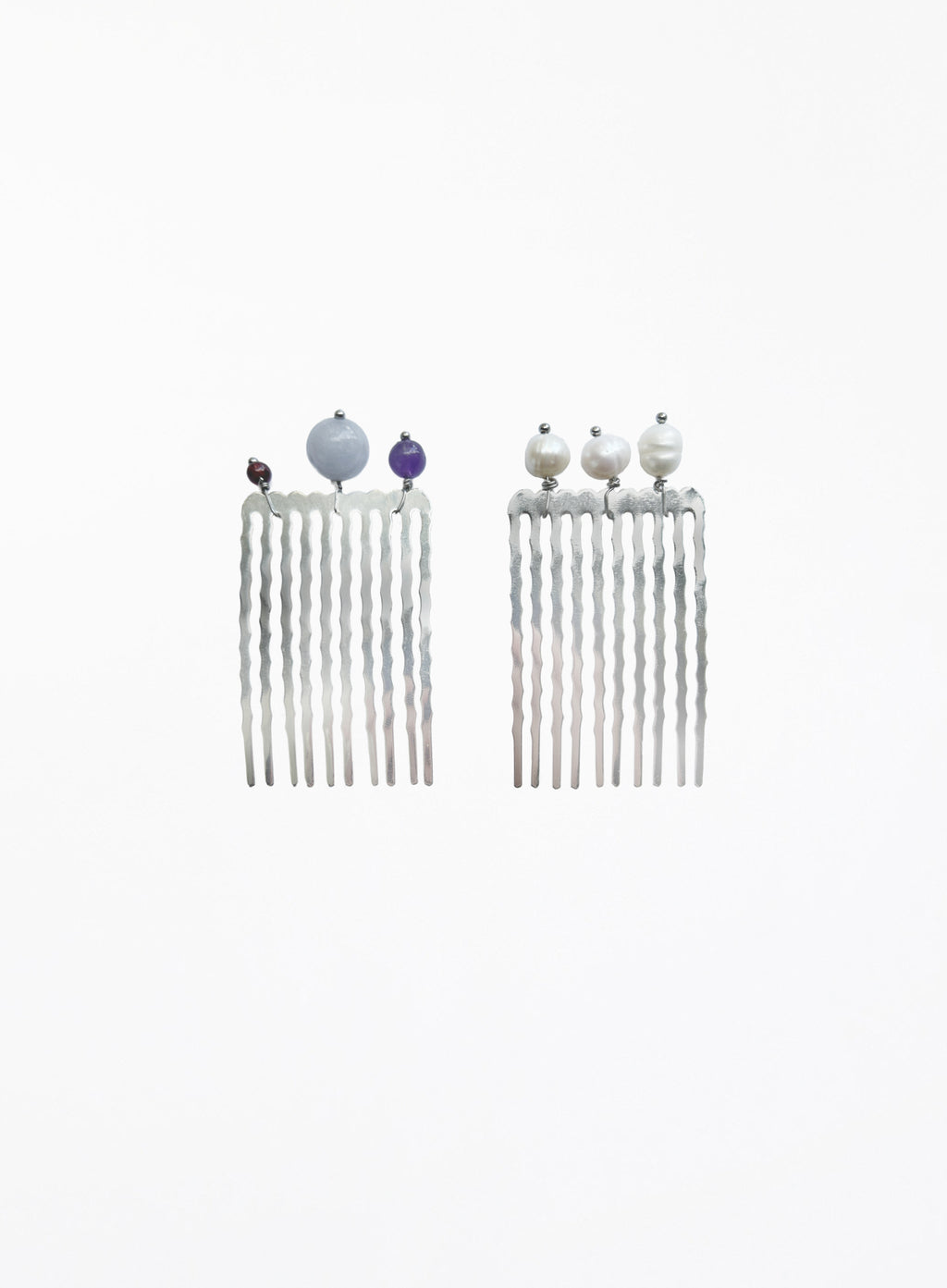 A pair of silver-toned long hair combs with twisted vertical prongs, decorated with small decorative beads at the top, shown on a plain white background.