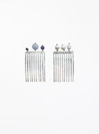 A pair of silver-toned long hair combs with twisted vertical prongs, decorated with small decorative beads at the top, shown on a plain white background.