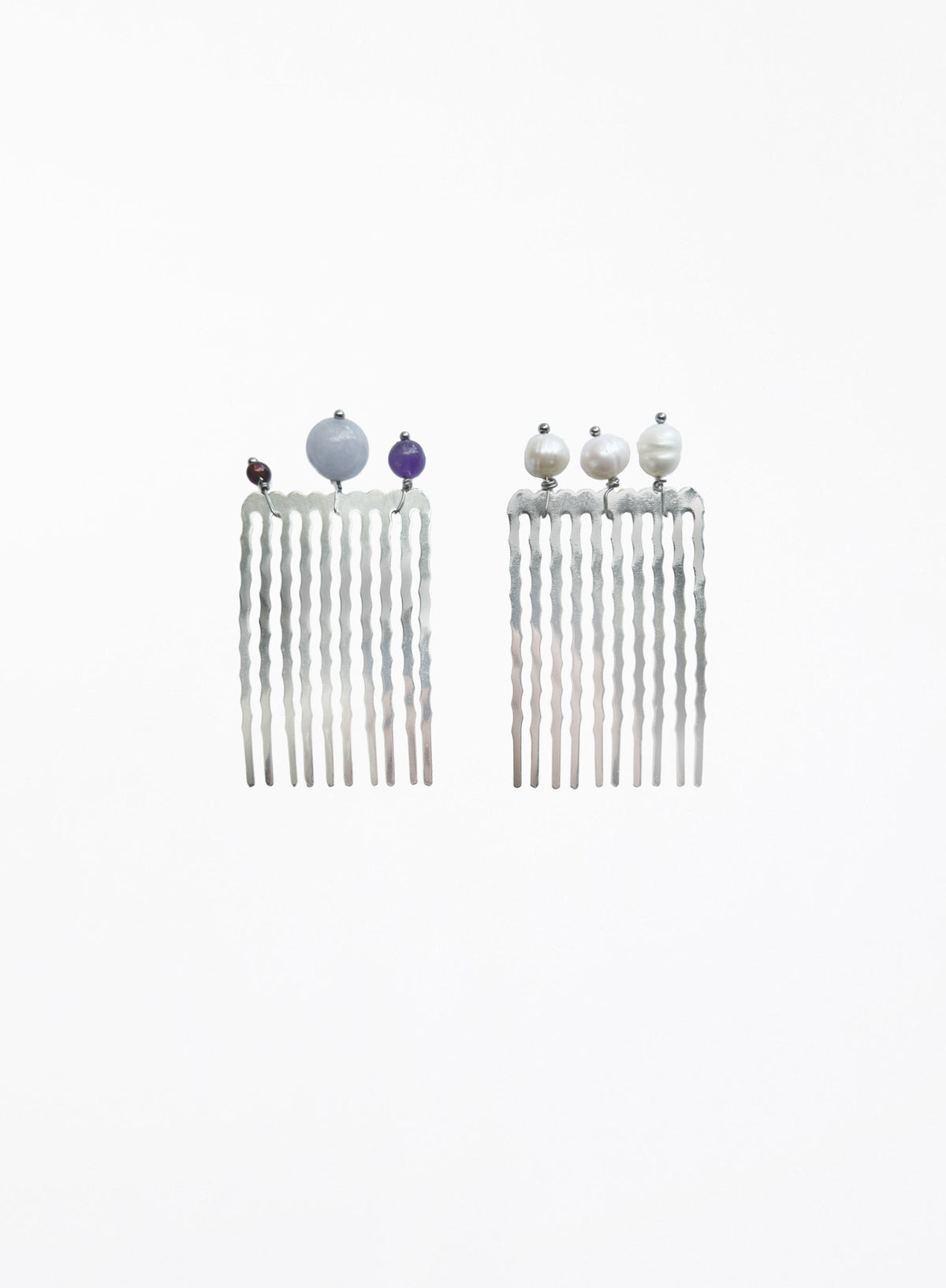 A pair of silver-toned long hair combs with twisted vertical prongs, decorated with small decorative beads at the top, shown on a plain white background.