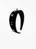 Black headband with green beads on a white background