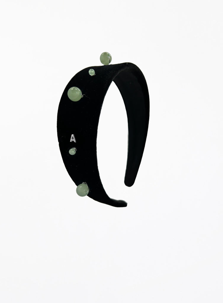 Black headband with green beads on a white background