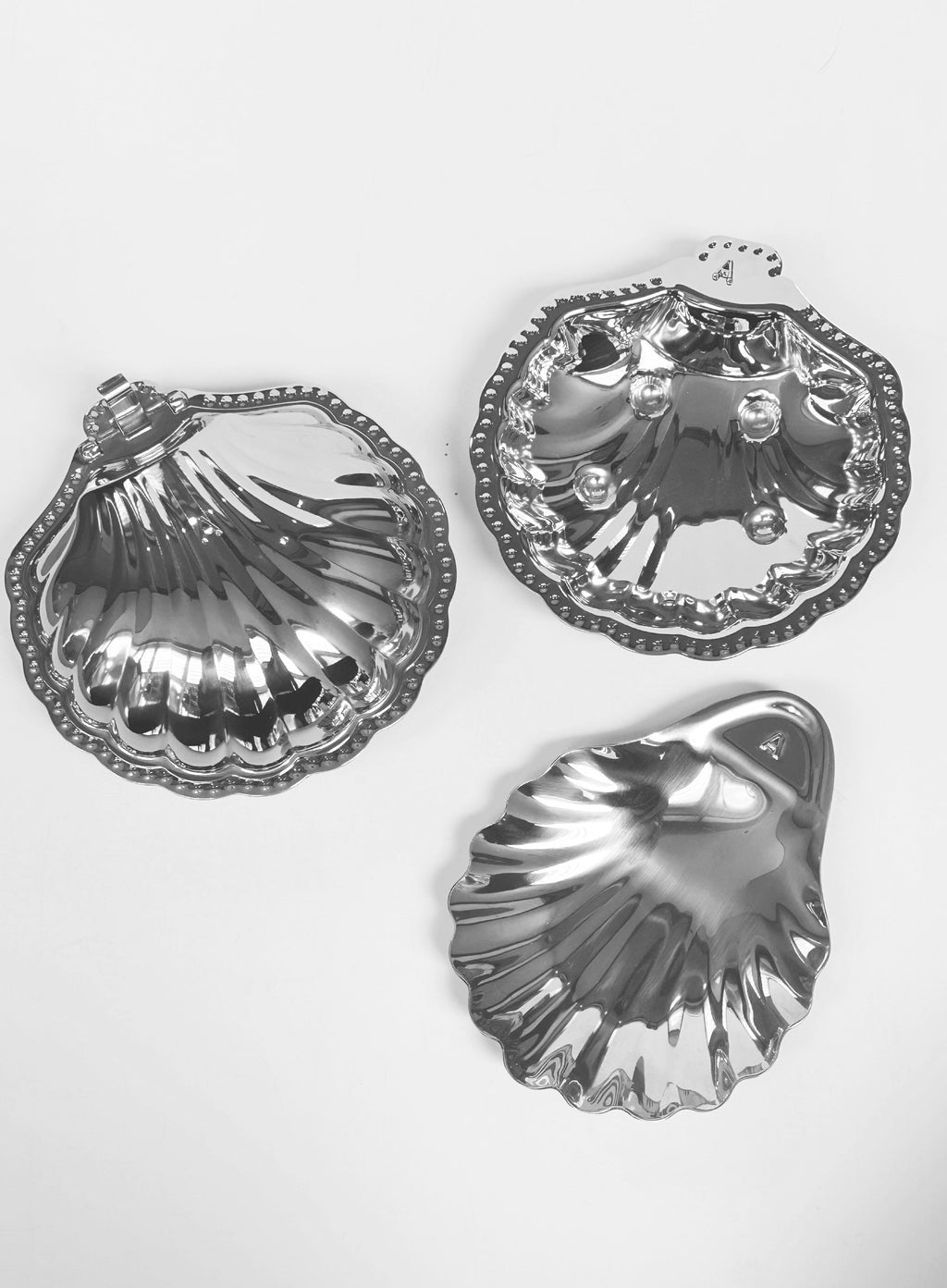 Three silver shell-shaped dishes on a white background