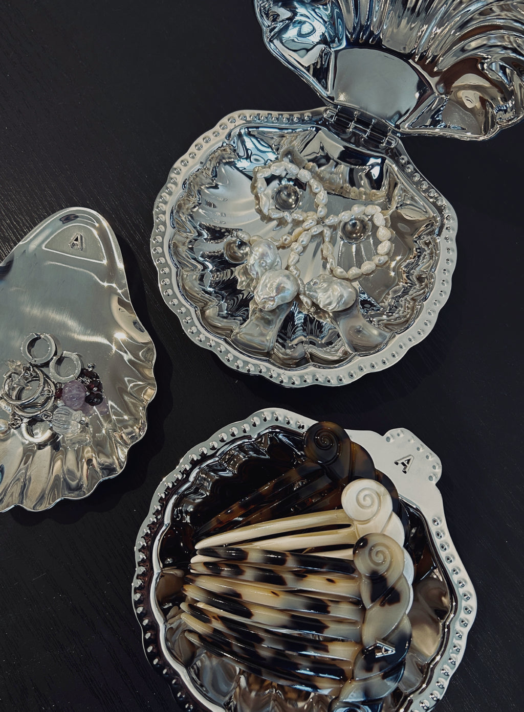 Decorative shell-shaped plates with intricate designs on a dark surface