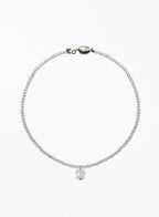 A delicate beaded necklace with a small faceted clear crystal pendant, displayed on a clean white background.