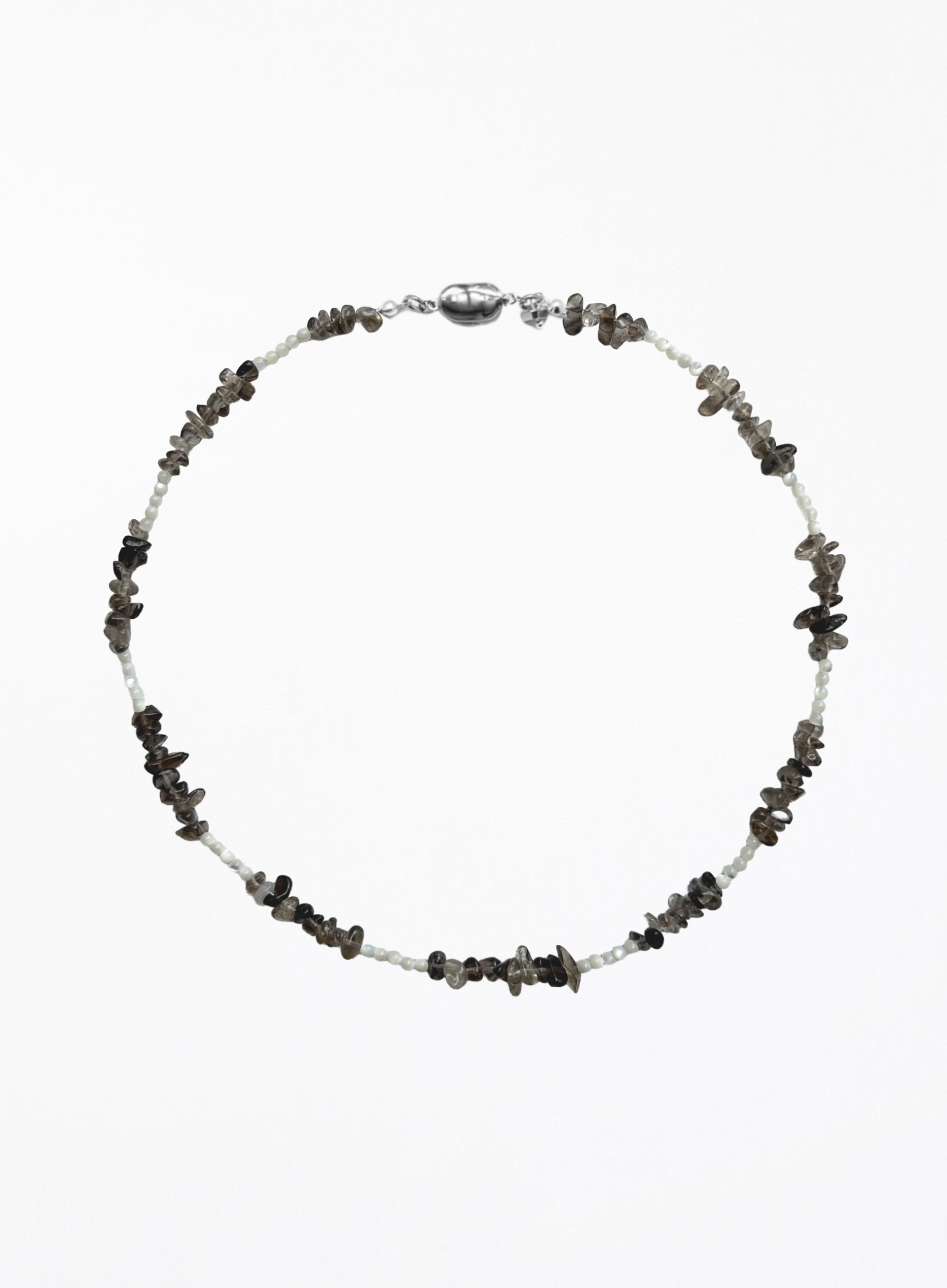 A beaded necklace featuring small white beads alternating with dark gray to black stone chips, finished with a polished silver clasp, shown on a plain white background.
