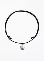 black cord necklace with baroque pearl in the center against white background