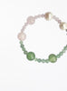 Beaded bracelet with pearls and green pink  stones on a white background
