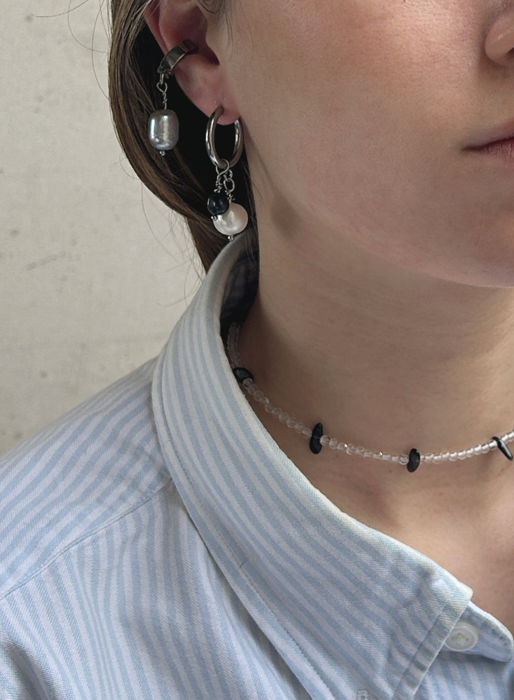 woman wearing pearl hoop earrings and grey pearl earcuffs
