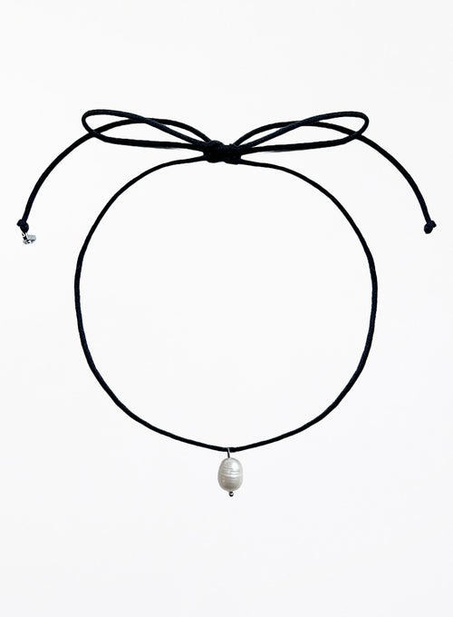 Black choker necklace with a pearl pendant on a white background
