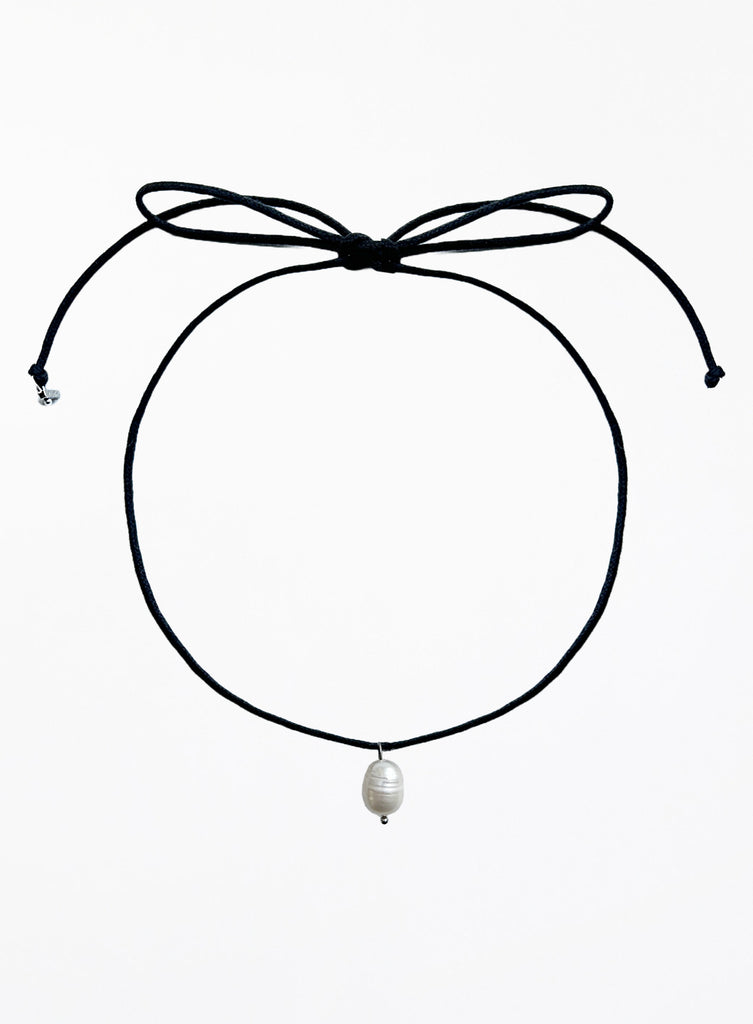 Black choker necklace with a pearl pendant on a white background
