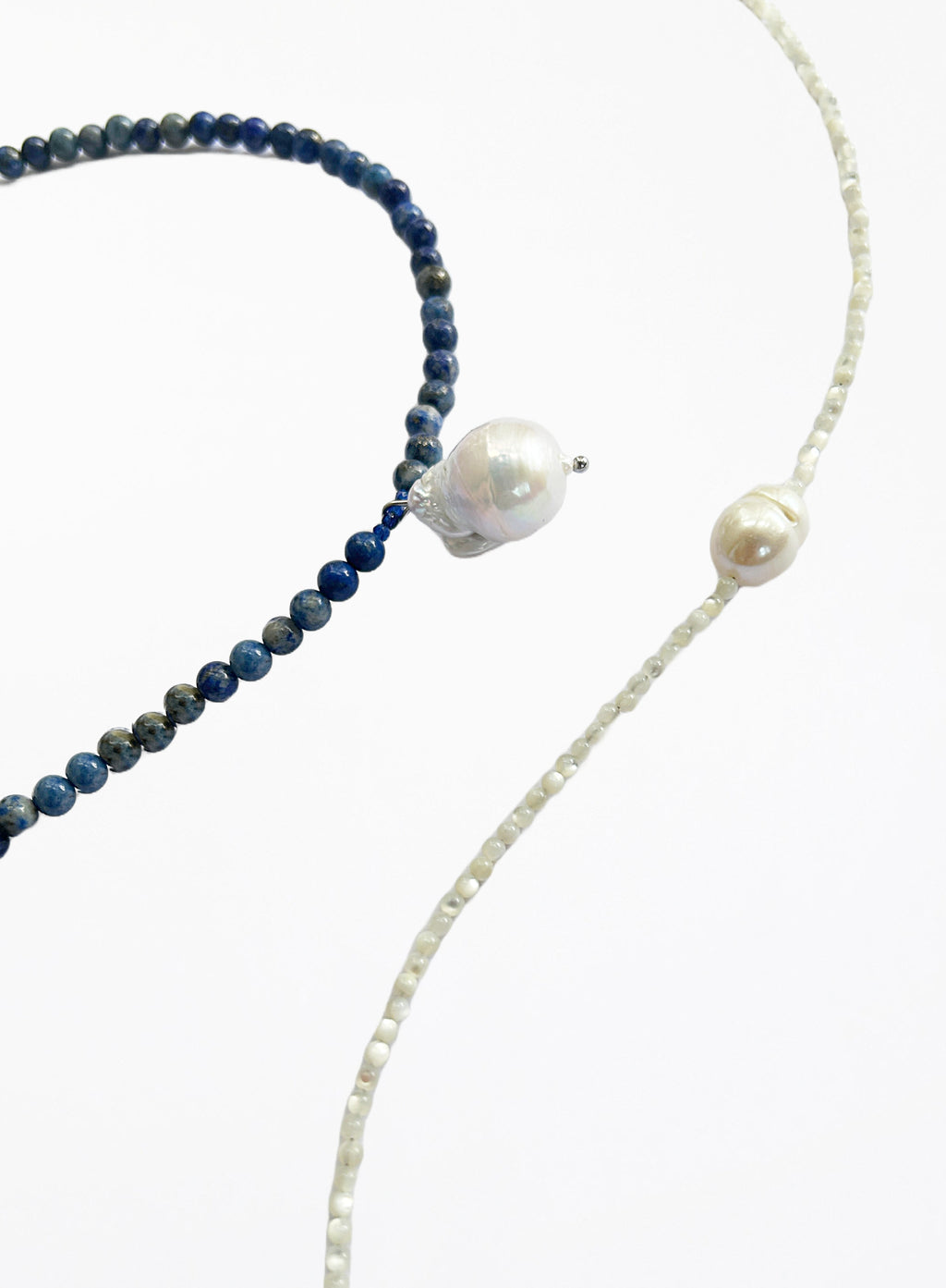 Two necklaces, one with blue beads and white pearls, the other with white beads and pearls, on a white background.