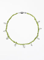Necklace with green beads and white beaded charms on a white background