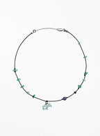 Necklace with green beads and a small charm on a white background