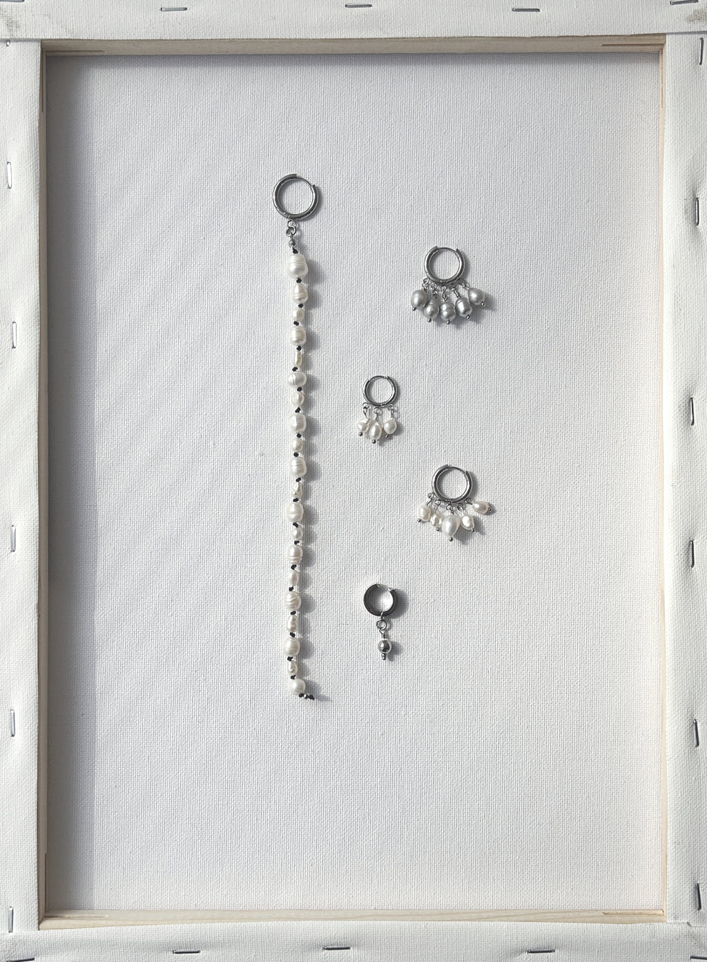flatlay of multiple pearl earrings on a wooden frame