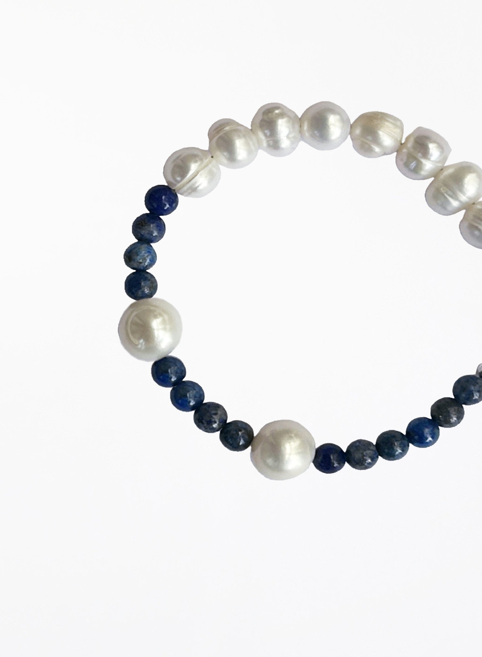 Bracelet with alternating white pearls and blue beads on a white background