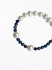 Bracelet with alternating white pearls and blue beads on a white background