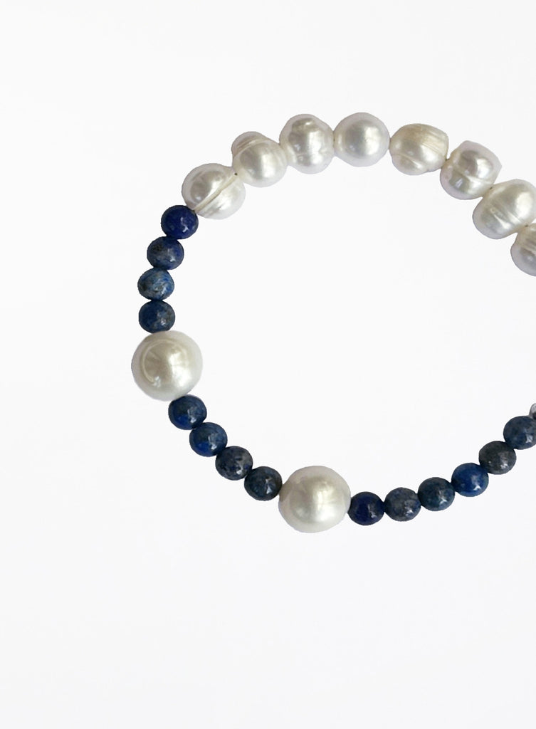 Bracelet with alternating white pearls and blue beads on a white background
