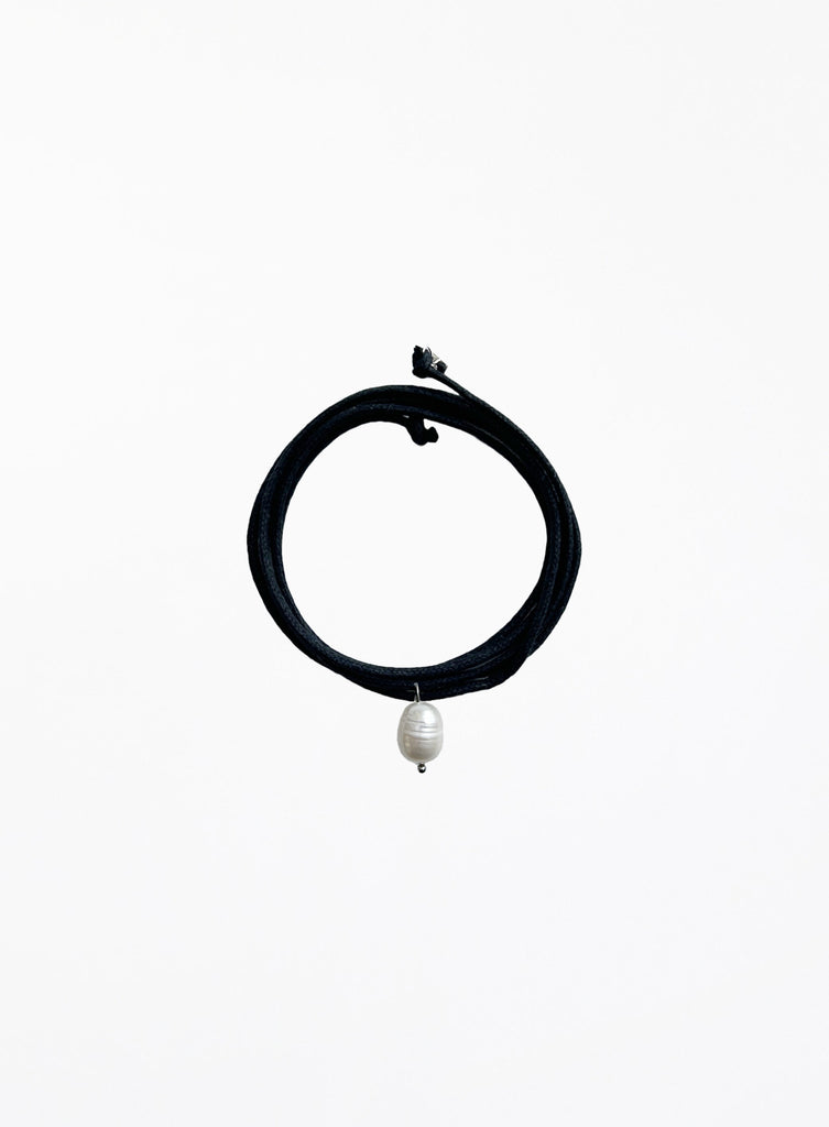 Black choker necklace with a pearl pendant on a white background