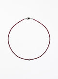 Thin garnet beaded necklace with tear drop charm on a white background