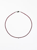 Thin garnet beaded necklace with tear drop charm on a white background