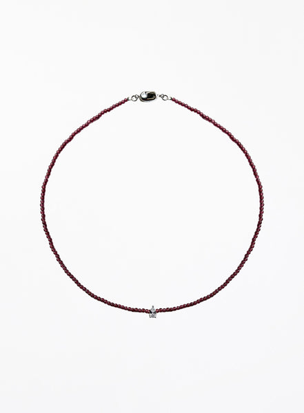 Thin garnet beaded necklace with tear drop charm on a white background