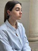 woman in blue stripe shirt wearing pearl earrings and beaded necklace